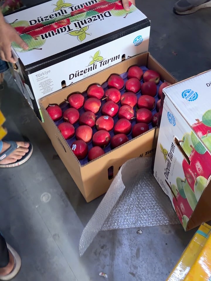 An apple carton opened at an angle among other cartons